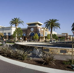 A large fountain with retail shops in the background